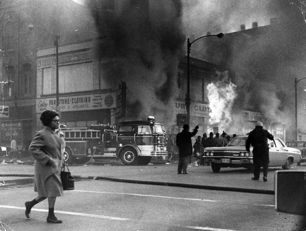A woman calmly walks down Madison street in chicago during the riots following the 1968 assassination of Martin Luther King Jr.