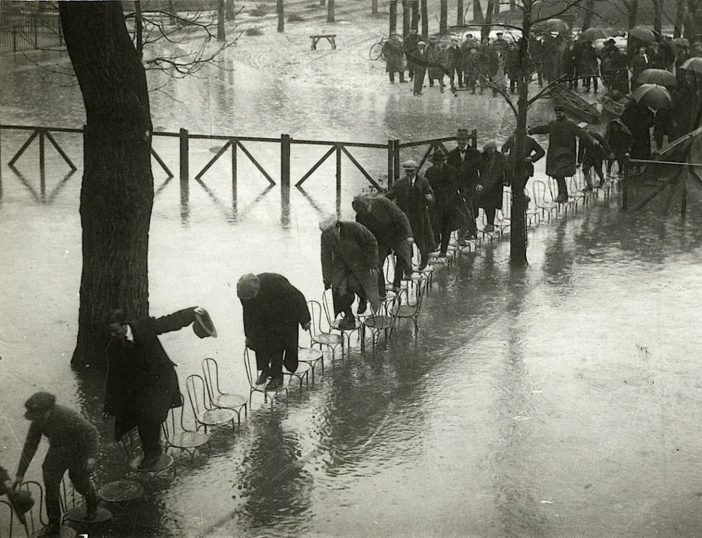 People walking on the chairs at the Maisons-Laffitte racecourse to escape the river Seine flood. Paris. 1924.
