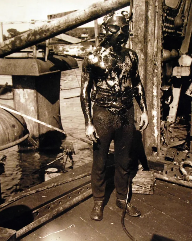 A diver as he ascends from the oily interior of the sunken battleship USS Arizona (BB 39). Photograph released May 23, 1943. 