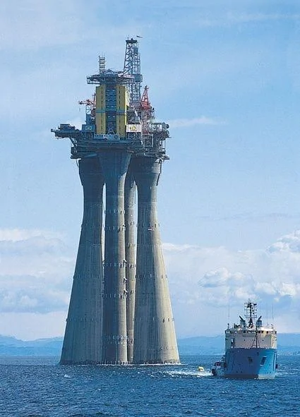 Troll-A, over 1500 feet tall, being taken out to sea before it&rsquo;s legs are sunk down to the ocean floor.